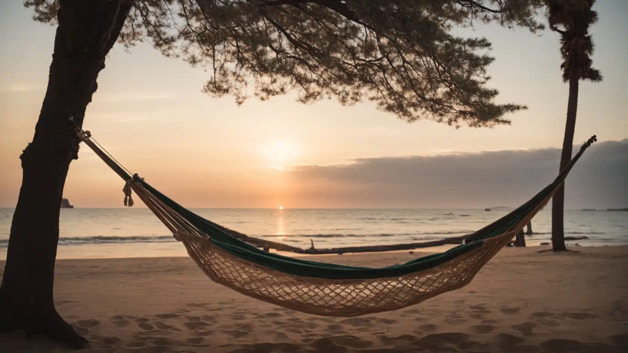 a serene beach at sunset with an empty hammock swaying gently, symbolizing tranquility and disconnection from work.